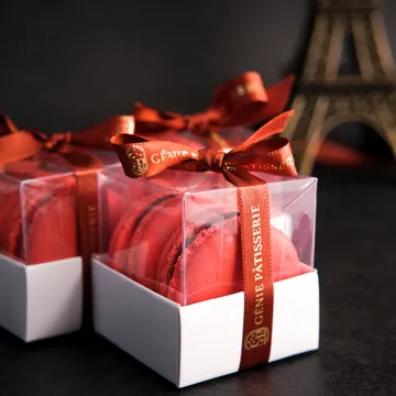 Caixas de lembrancinha brancas com laço vermelho, uma delas aberta.